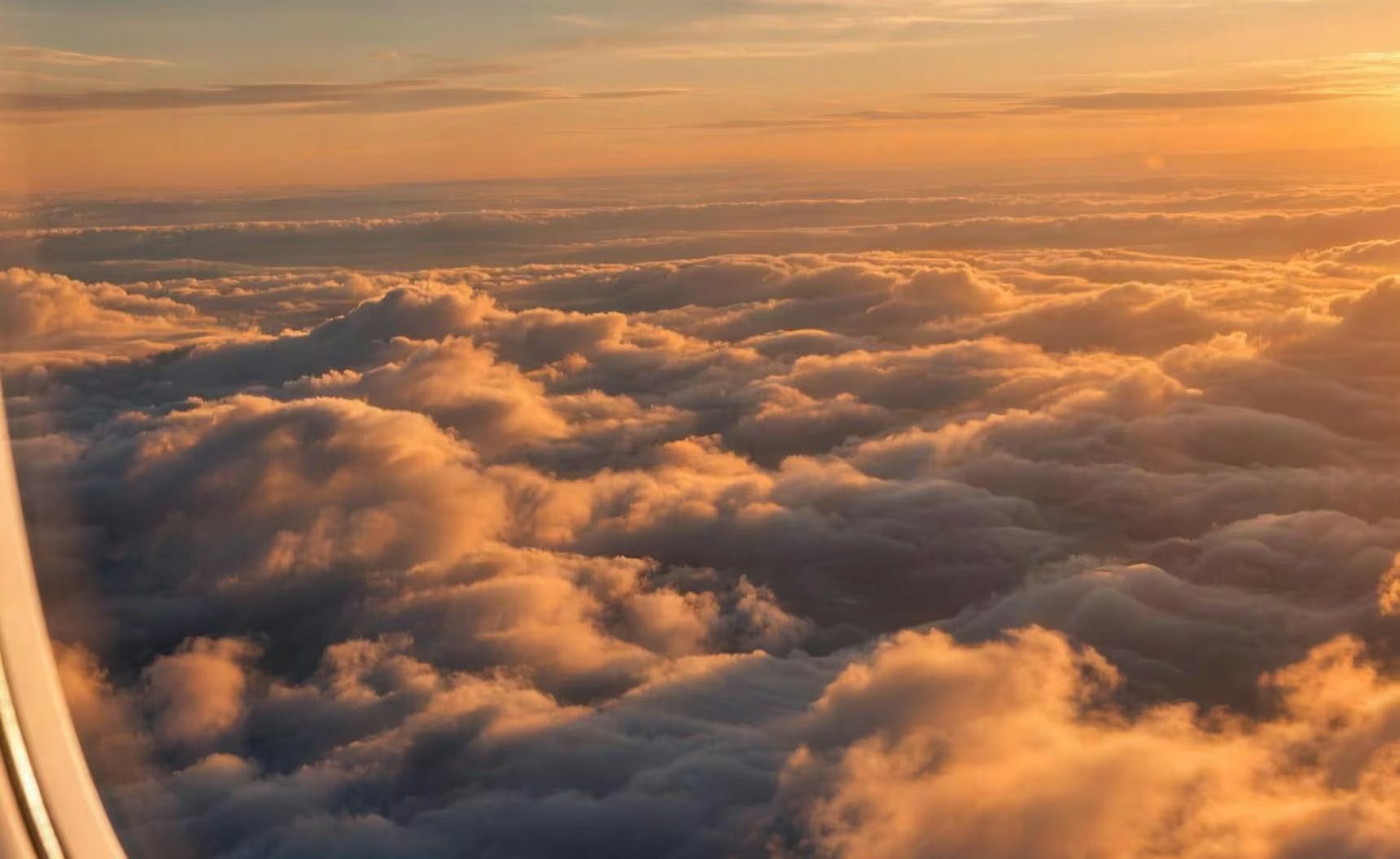 Sunset over a sea of clouds, seen from a private jet